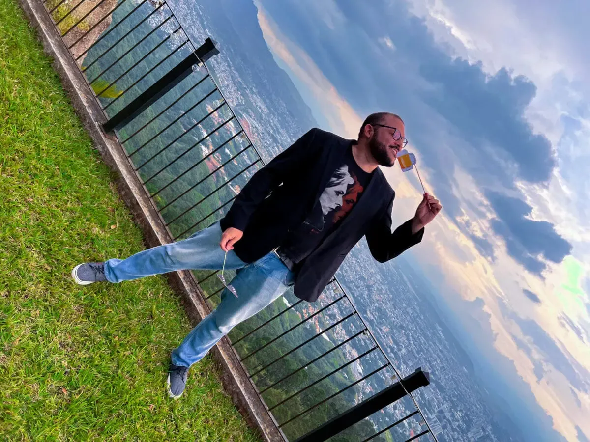Andes Development team member posing playfully with a photo prop during the agency's 12th anniversary celebration, with a panoramic view of the city in the background. It reflects the company's positive, dynamic workplace culture.