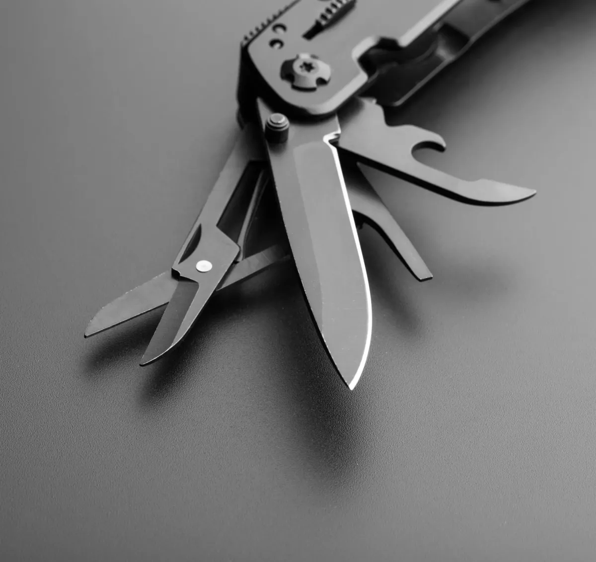 Black-and-white photograph of an open multi-tool Swiss Army knife showing its various tools. It symbolizes the value proposition as a technological 'Swiss Army knife,' acting as a strategic extension of the business to solve problems with the exact team of experts.