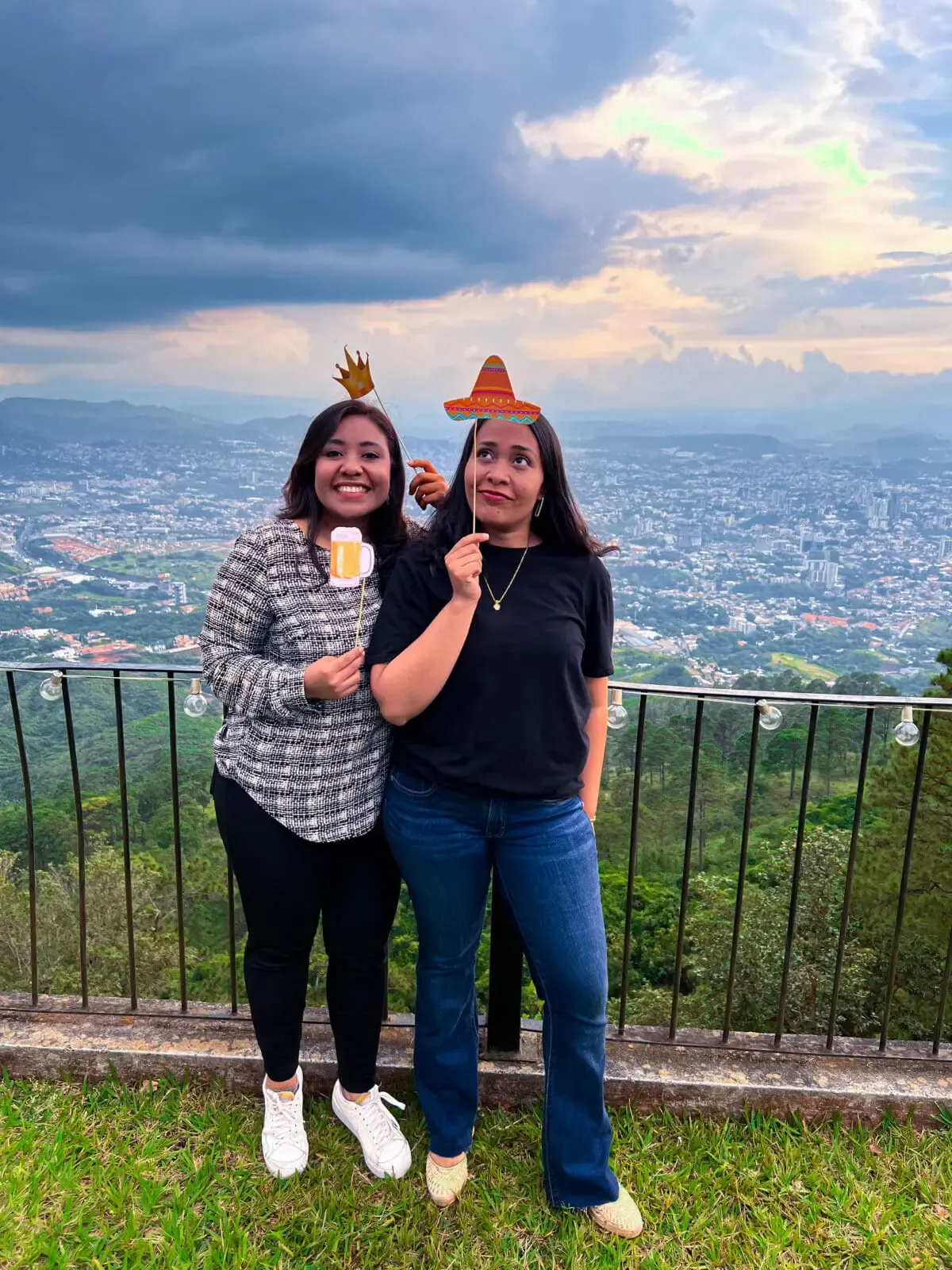 Two members of the Andes Development team posing cheerfully with festive photo props (a hat and a beer) at the agency's 12th anniversary gathering, showing the company's positive culture.